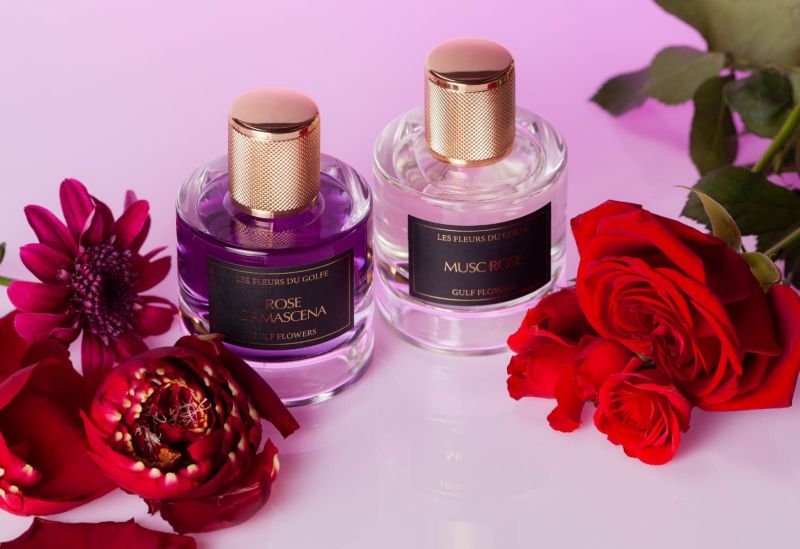 Une photo illustrative de deux parfums de la marque les fleurs du golfe posés à coté de fleurs de rose.