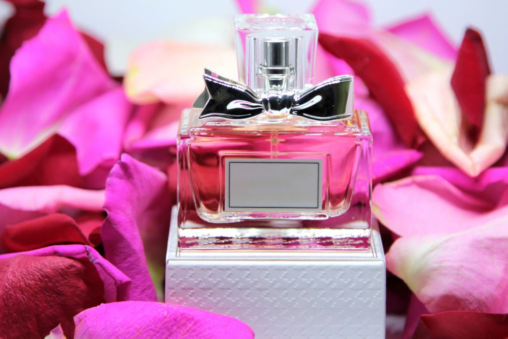 An illustrative photo of a perfume bottle surrounded by rose petals.