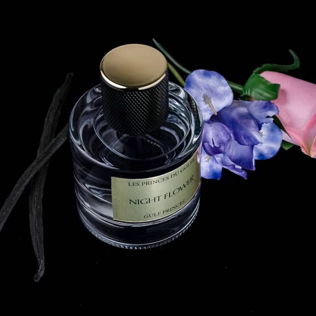 Une photo du parfum doux Night Flower à coté de gousses de vanille et de fleurs.